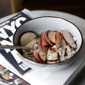 A bowl of oatmeal alternative with apples slices on top.